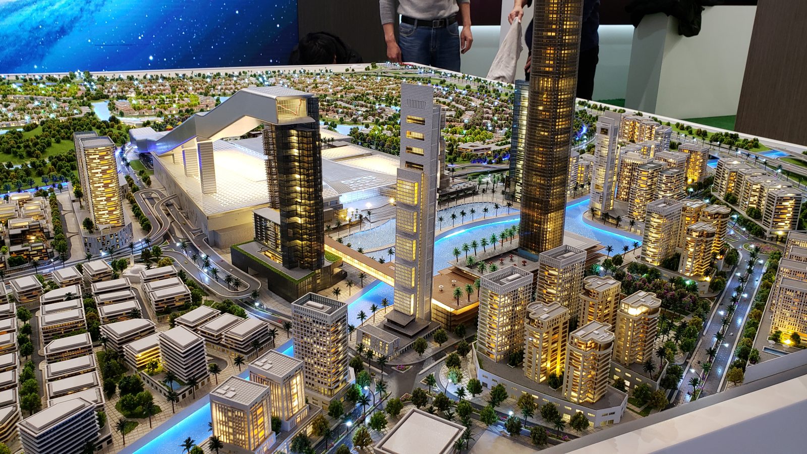 Central Maktoum City scale model with tall glass towers, mall, waterway and villa districts under starry backdrop